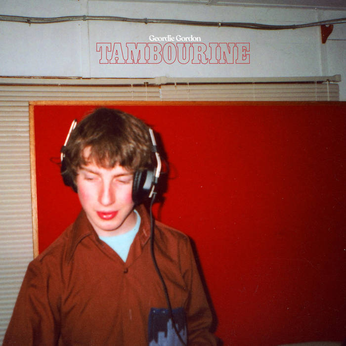 image shows a man with light brown hair wearing a brown button up shirt and headphones