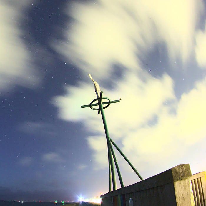 A crudely built device sits atop an unspecific structure; clouds swirl past in the background.
